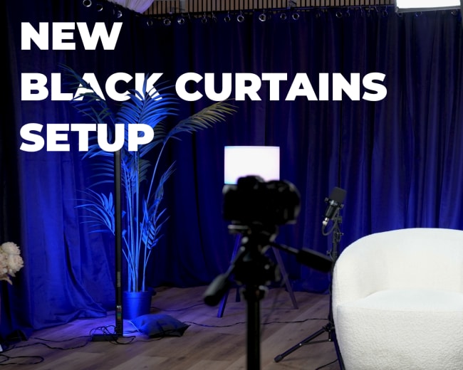 The image shows a studio setup featuring black curtains, a white chair, a small side table, a camera on a tripod, and a decorative globe in the background.