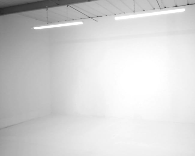 The image shows a plain, empty white room with two overhead lights illuminating the space.