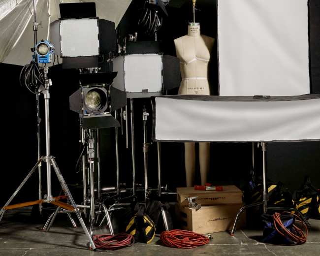 A photography setup with lights, a mannequin, and various equipment placed against a black backdrop.