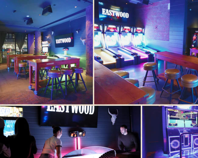The image depicts a modern entertainment venue featuring colorful lighting, game machines like skeeball and air hockey, and a bar area with wooden tables and stools.