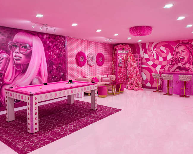 The room features a vibrant pink color scheme with a pool table, decorative wall murals, and stylish seating areas.