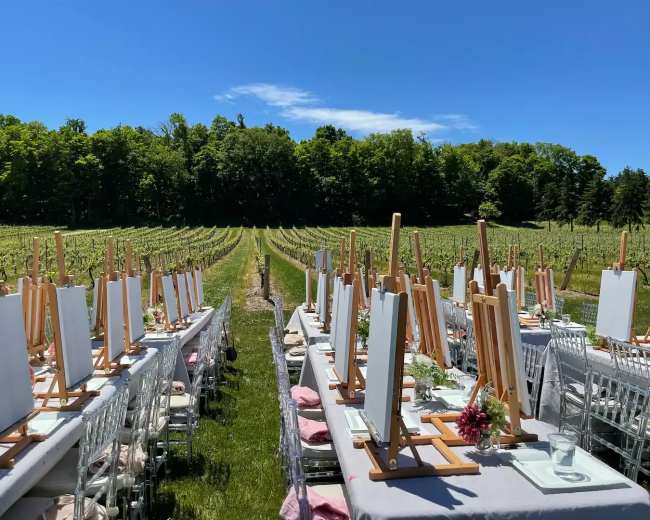 A wooden pavilion sits beside a pond surrounded by manicured lawns and trees with autumn foliage.