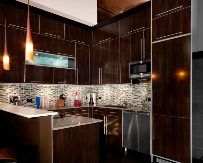 The kitchen features dark wooden cabinetry, a mosaic tile backsplash, and modern stainless steel appliances.