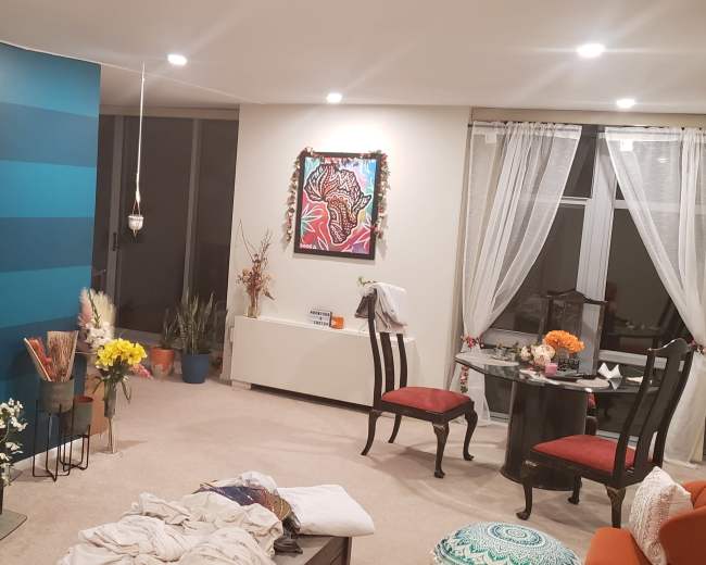 The image shows a living room with a blue striped accent wall, a large television, a dining table with chairs, and various decorations including flowers and artwork.