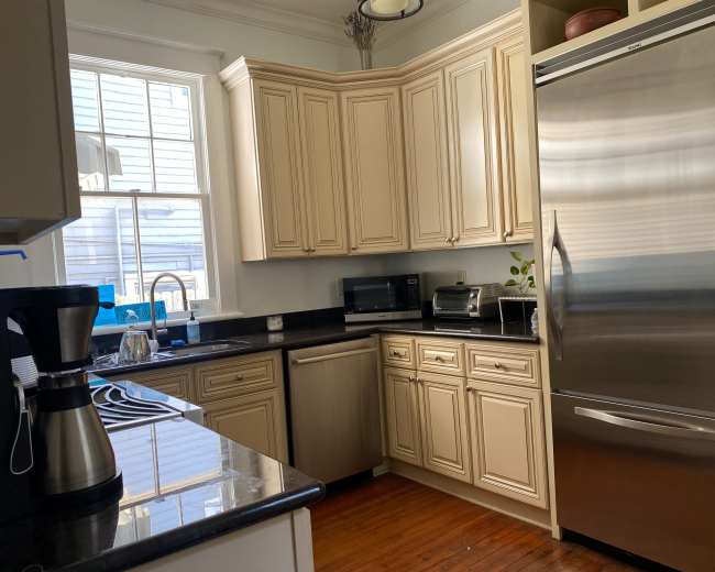 The image shows a modern kitchen featuring beige cabinetry, stainless steel appliances, and a window allowing natural light to illuminate the space.