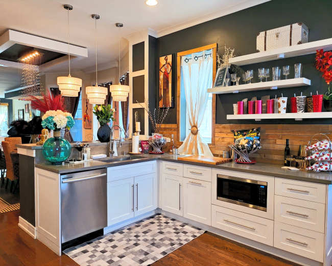 The image shows a modern kitchen with white cabinetry, a gray countertop, an island with a sink, and decorative shelves displaying various items.