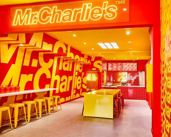 The image shows the interior of a brightly colored restaurant named "Mr. Charlie's," featuring red and yellow walls adorned with the restaurant's name.