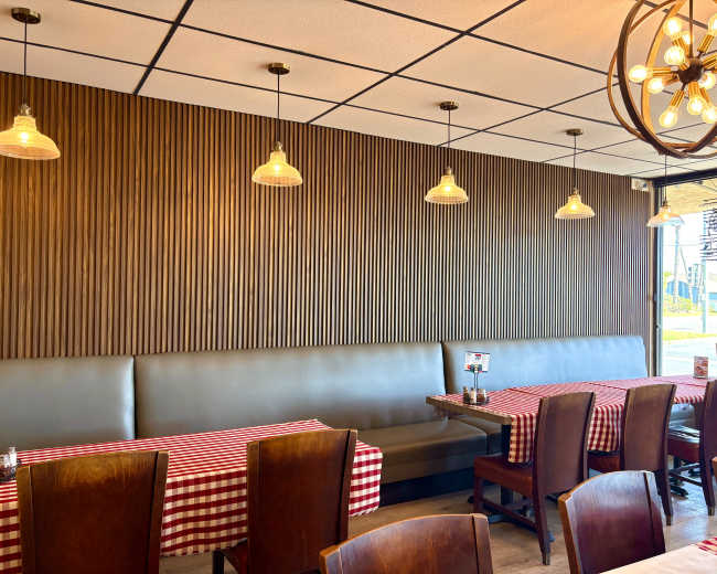 The image shows a restaurant interior with wooden paneling and red-and-white checkered tablecloths on the tables, accompanied by pendant lighting.