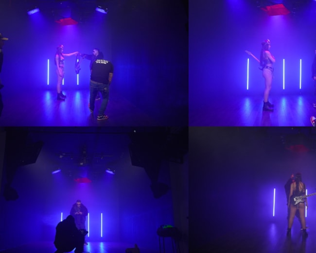 The image shows a staged photo shoot with two models posed under vibrant lighting, while photographers adjust equipment and settings in the studio.