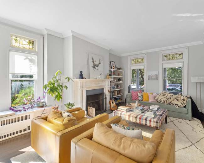 The living room features a fireplace, a large window, and seating arranged around a coffee table.