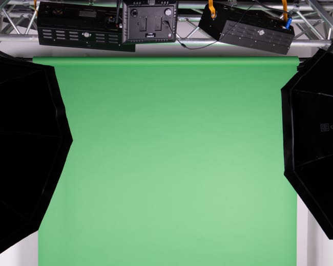 The image shows a green backdrop with studio lights positioned on either side in a photography studio.