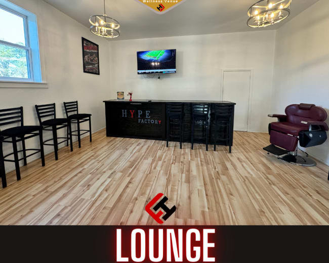 The image shows a clean, modern lounge area with a bar counter, seating, and a large screen mounted on the wall.