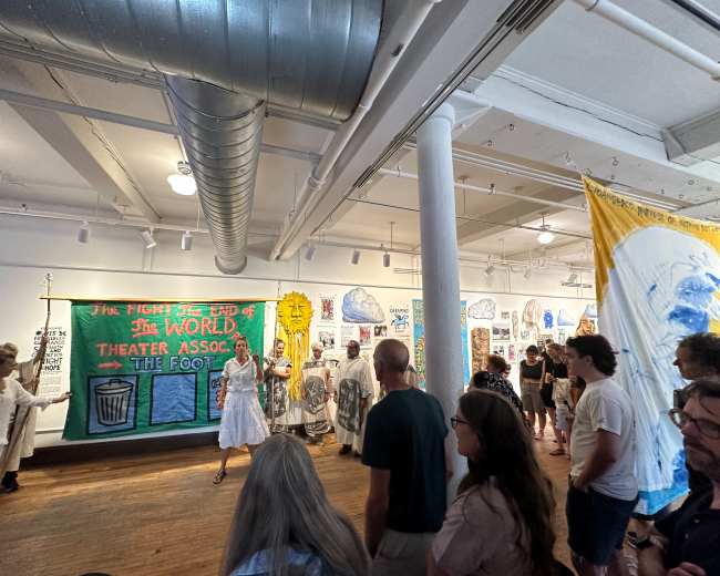 A group of people gathers in an art gallery featuring large banners and paintings on the walls.