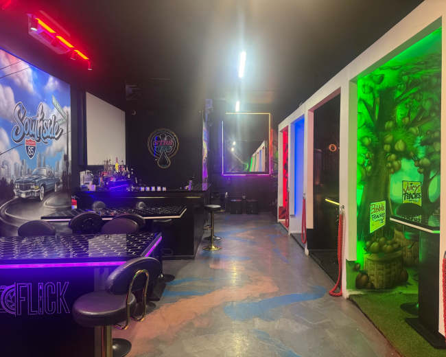 The image shows a vibrant interior of an entertainment venue with colorful lighting, a bar area, and a section featuring themed wall designs.