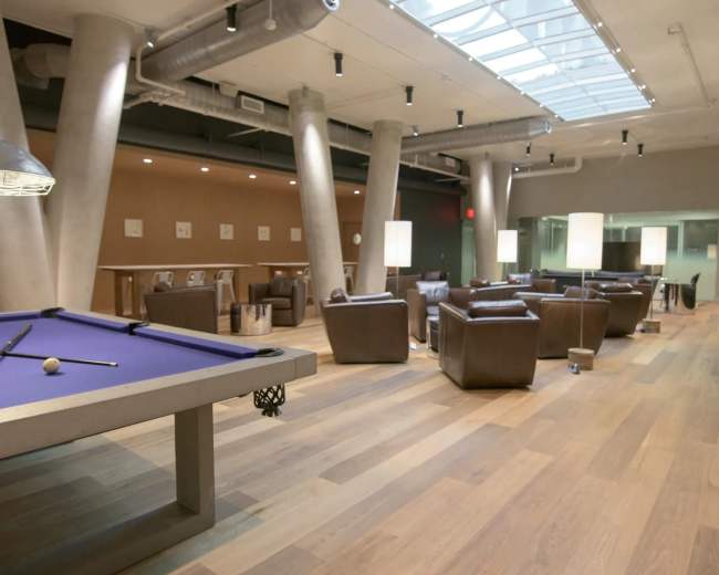A spacious indoor lounge area featuring a billiards table, leather seating, and modern lighting fixtures.