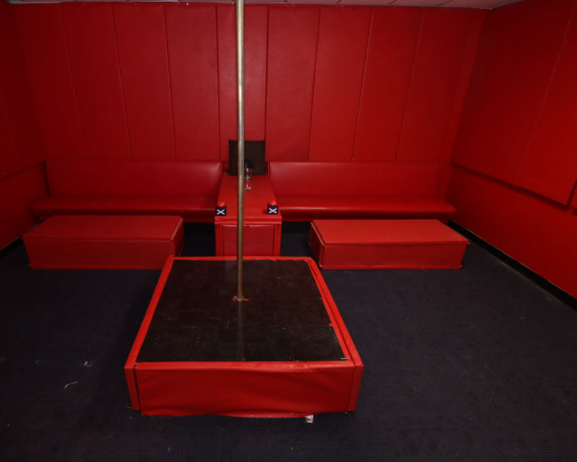 A small room with red walls and seating, featuring a central pole mounted on a square platform.
