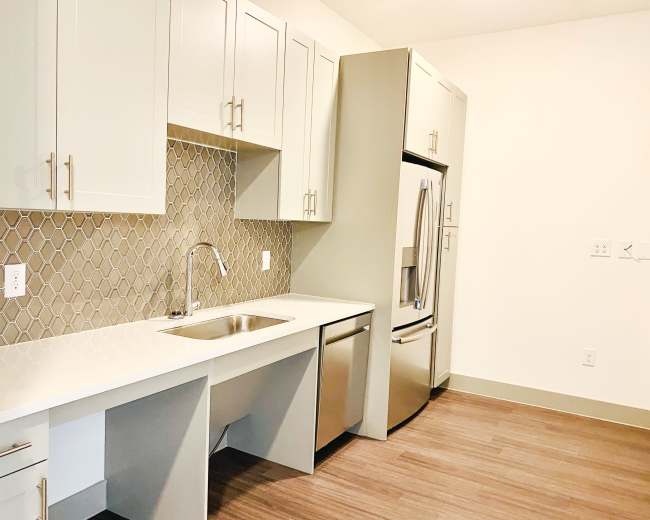 A modern kitchen features light-colored cabinetry, a stainless steel refrigerator, and a subway tile backsplash.