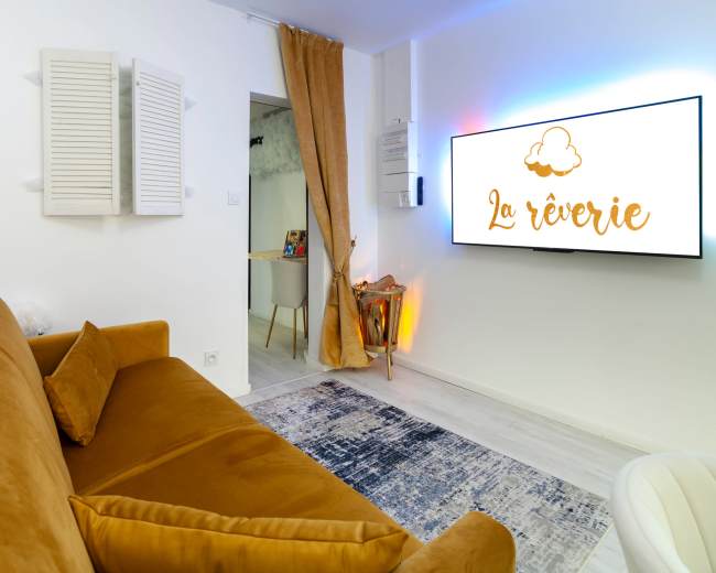 The image shows a cozy room with a brown sofa, a modern television displaying the words "La rêverie," and light-colored walls.