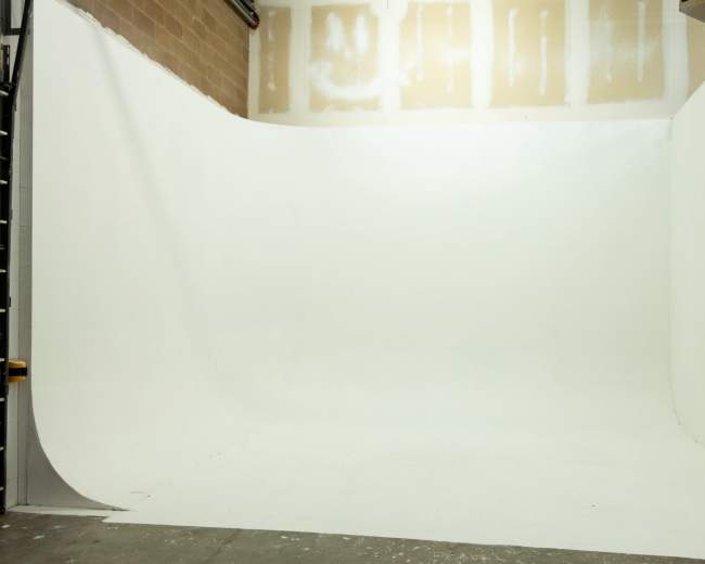 The image shows a photography studio with a seamless white backdrop and no visible props or subjects.