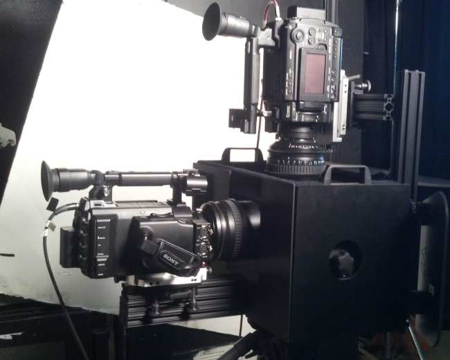 A black camera rig with two different cameras mounted on it is positioned against a backdrop.