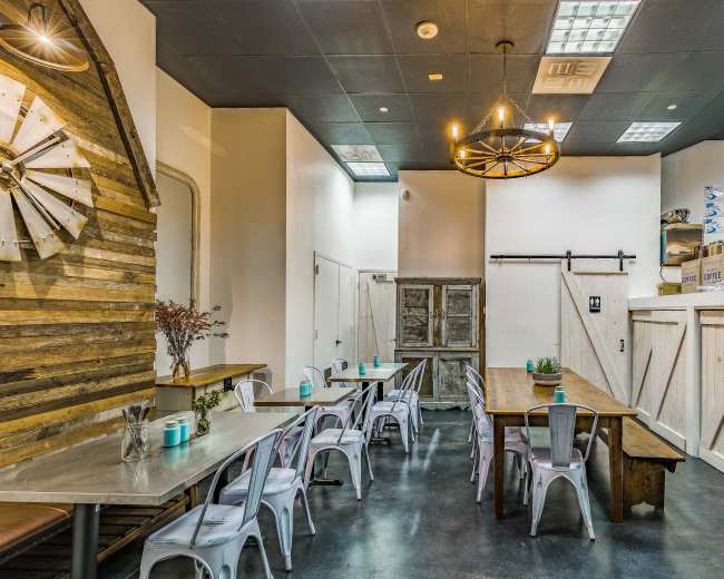 A modern restaurant interior featuring wooden accents, a mix of tables and chairs, and a simple layout.