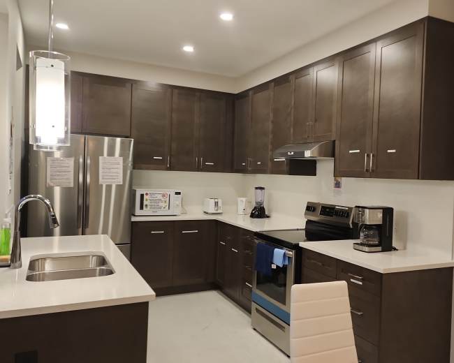 The image shows a modern kitchen with dark wood cabinetry, stainless steel appliances, and a white countertop.