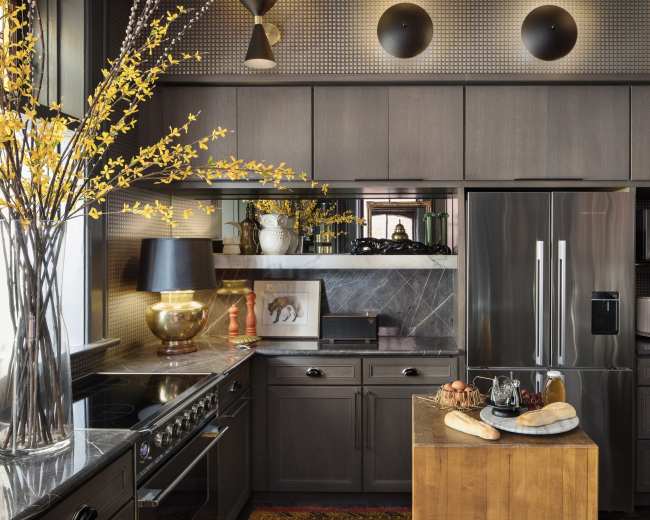 A modern kitchen features dark cabinetry, stainless steel appliances, and a wooden island with bread and eggs.