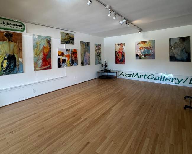 The image shows an art gallery with several paintings displayed on the walls and a wooden floor.