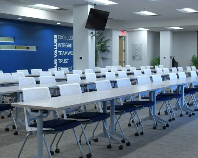 A spacious conference room set up with multiple rows of tables and chairs arranged for a meeting.