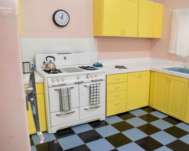 The kitchen features yellow cabinetry, a white stove, and a blue and black checkered floor.