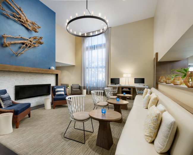 The image shows a modern lounge area featuring a fireplace, comfortable seating, and a large blue wall with decorative artwork.