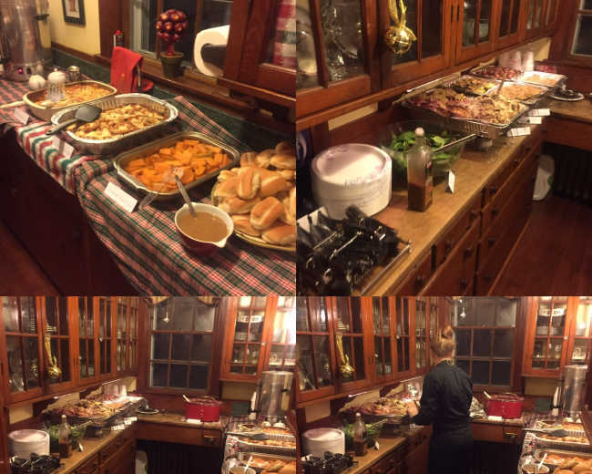 A kitchen with a buffet setup, featuring various dishes such as roasted vegetables, baked goods, and beverages, along with a staff member preparing food.