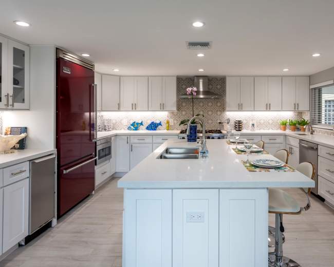 A modern kitchen with stainless steel appliances, white cabinetry, and a central island featuring bar stools.