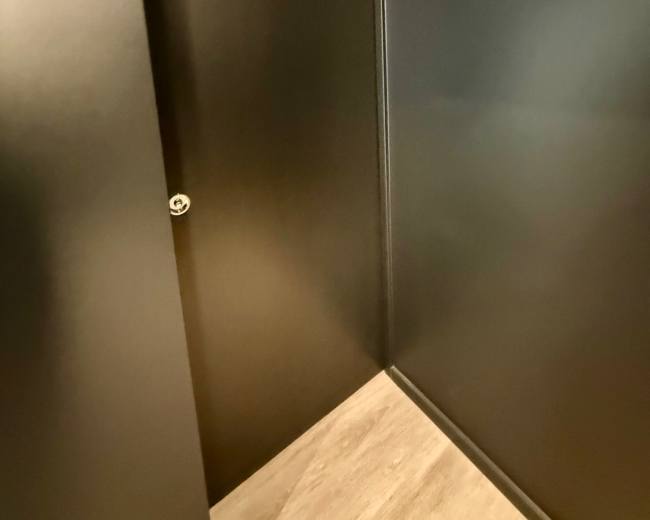 A dark hallway features a closed door on the left side and a wall painted in the same color.