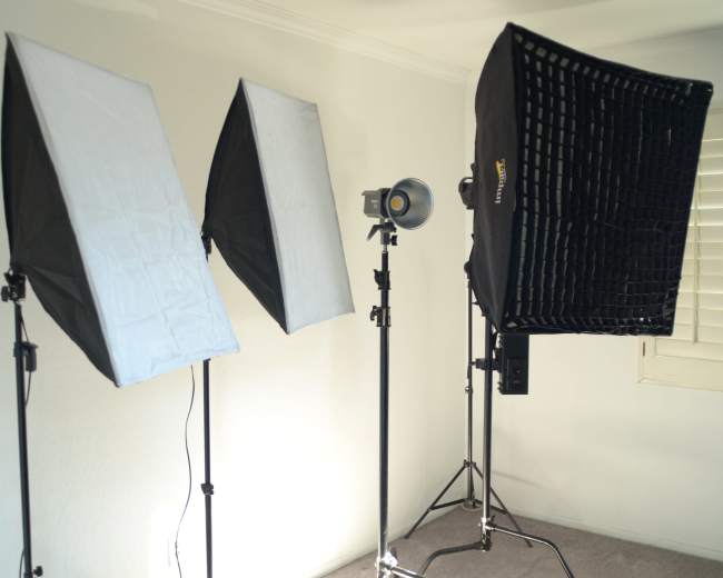 Three studio lighting setups arranged in a room with white walls and carpet.