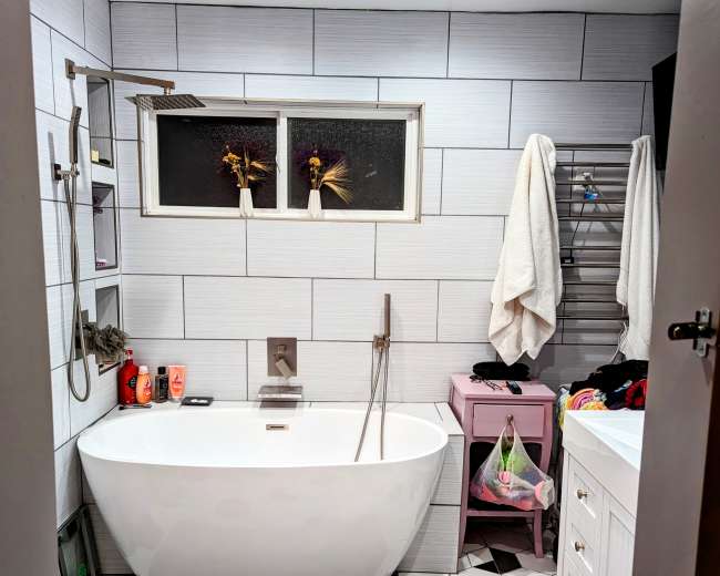 A modern bathroom featuring a freestanding bathtub, a shower with a glass door, a white vanity, and hexagonal tiled flooring.