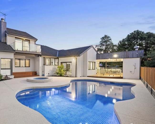 The image shows a modern two-story house with a swimming pool and a hot tub in the backyard.