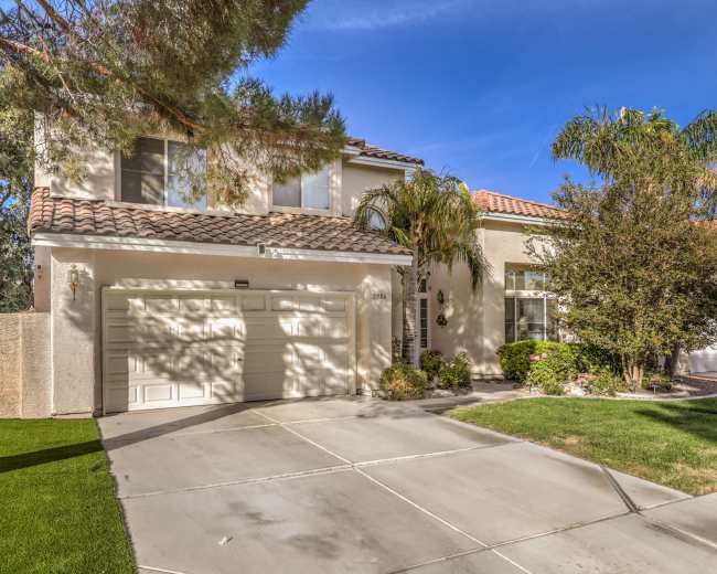 A two-story house with a tiled roof, a two-car garage, and a well-maintained front yard.