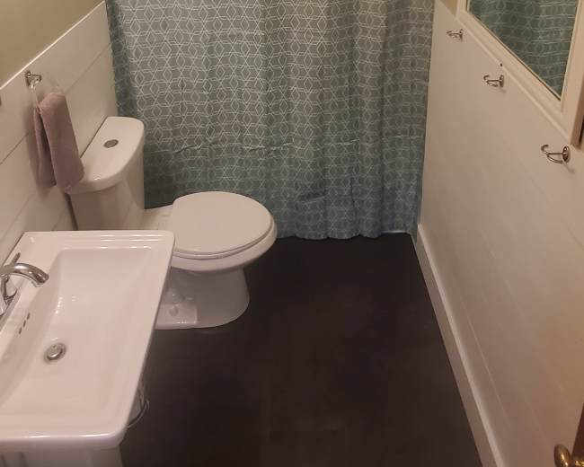 A small bathroom features a toilet, sink, and a shower area separated by a patterned curtain.