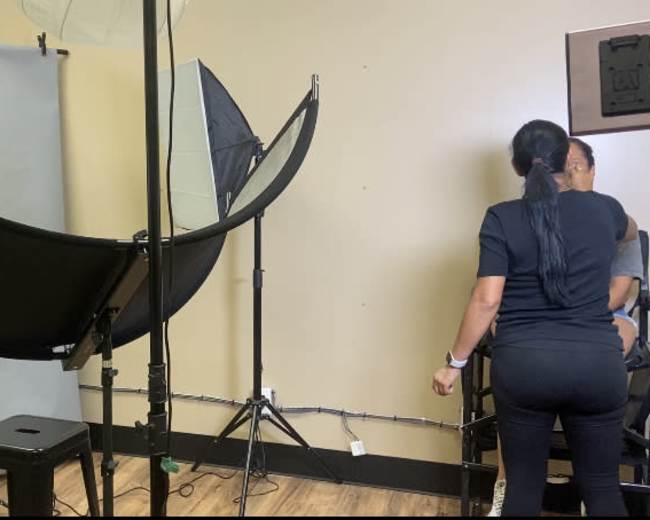 A photography studio setup features a backdrop, lighting equipment, and a person preparing for a photo shoot.