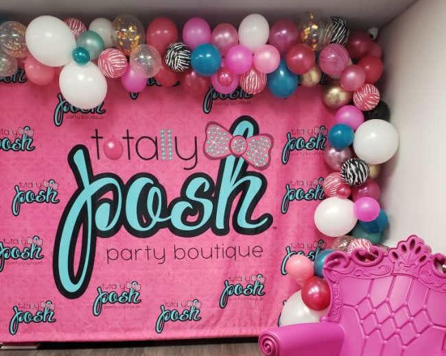 A vibrant party backdrop with balloons in pink, white, and black, alongside a bright pink chair.