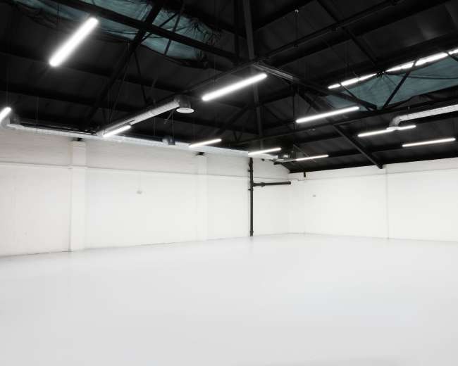 The image shows a spacious, empty industrial room with a high ceiling and bright overhead lighting.