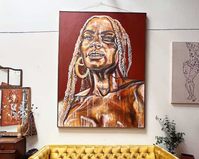 The scene features a vibrant yellow velvet sofa positioned in front of a large artwork depicting a woman, with a neutral-toned wall and various decorative elements surrounding the area.