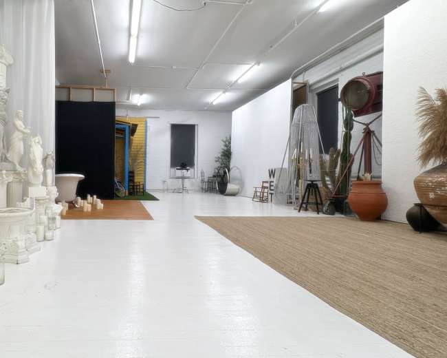 The image shows a spacious interior containing classical sculptures, soft lighting, and various decorative elements across a white floor.