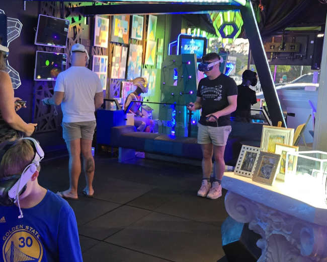 People are using virtual reality headsets in a colorful, interactive gaming space.