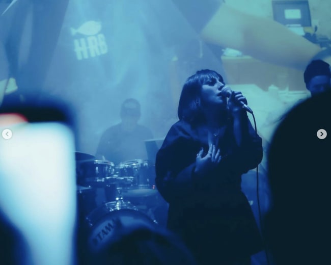 A singer performs on stage in front of a visually immersive backdrop during a live event.