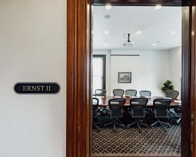 A conference room named "ERNST II" is visible through an open door, featuring a large table surrounded by chairs and a projector on the ceiling.