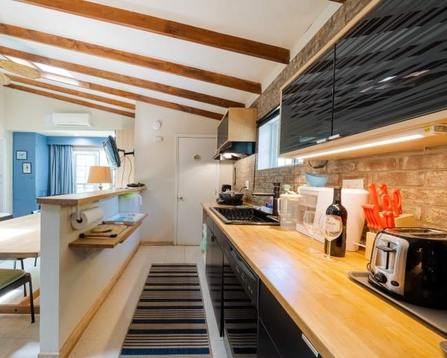 The kitchen features wooden beams on the ceiling, a black countertop, and a dining area with a wooden table and chairs.