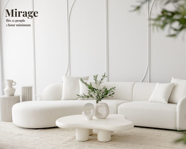 The image features a modern, minimalist living room with a white curved sofa, a sculptural coffee table, and decorative greenery.