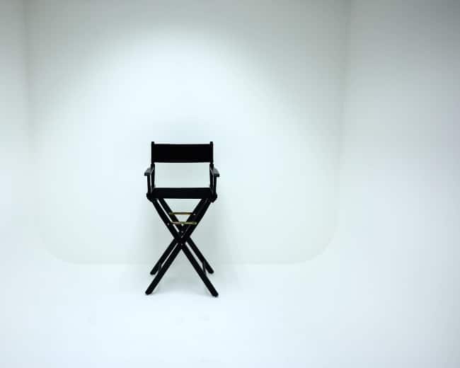 A black director's chair is positioned in the center of a plain white background.